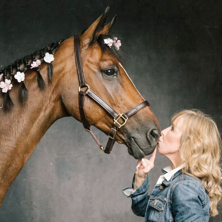 Voice over talent Anne Ghrist kissing the nose of a horse. Anne spent years riding horses in competitions before becoming a voice actor. 